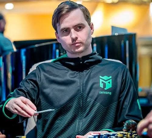 Martin Kabrhel seated at a poker table in an Entropiq jacket, holding a pen behind a stack of chips